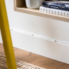 a book shelf with books on top of it next to a rug and a yellow chair