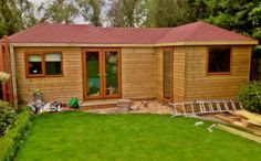 a small wooden cabin with windows and green grass