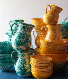 a stack of yellow and green vases sitting next to each other on top of a table