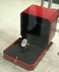 an engagement ring in a red box on the ground