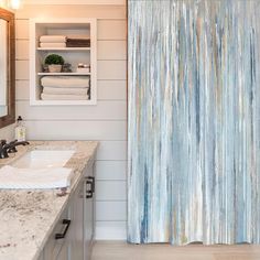 a bathroom with a blue shower curtain next to a white sink and counter top in front of a mirror