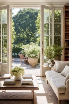 a living room filled with lots of furniture next to a large open window covered in plants