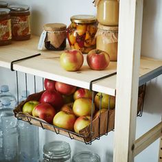 apples are in baskets on the shelves next to jars