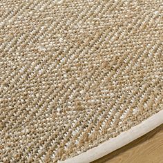 a close up view of an area rug on a wooden floor with white and beige colors