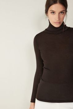 Long-sleeve high-neck tubular top made from a wool-silk blend. Fitted Elegant Merino Wool Tops, Elegant Fitted Merino Wool Tops, Chic High Neck Fine Knit Turtleneck, Chic Fine Knit High Neck Turtleneck, Stretch Merino Wool Turtleneck Top, Elegant Mock Neck Turtleneck Top For Winter, Merino Wool Turtleneck Top, Wool Tops With Seamless Collar For Fall, High Neck Merino Wool Tops For Fall