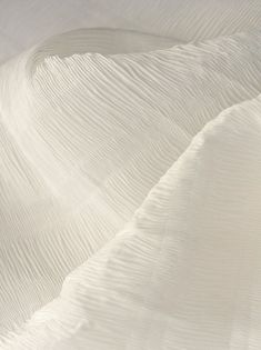 the white sheets are folded neatly on top of each other in an abstract pattern that resembles wavy lines