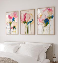 two paintings on the wall above a bed in a room with white sheets and pillows