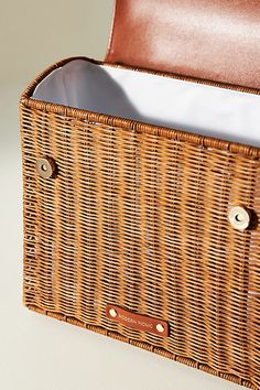 a brown wicker basket with leather linings on the bottom and inside, sitting on a white surface