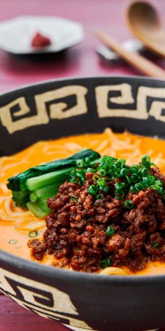 a bowl filled with soup and vegetables on top of a table