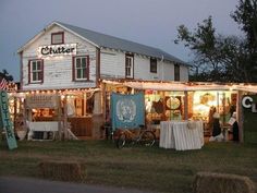 a store with lights and decorations on the front lawn at night, next to hay bales