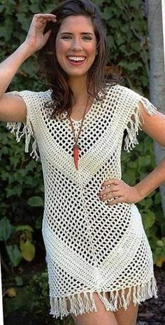 a woman wearing a white crochet dress with fringes on the sides and smiling