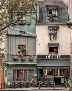 an old building with people sitting at tables outside