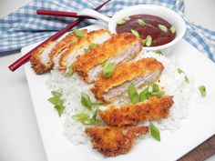 some food is on a white plate with chopsticks and sauce in the bowl