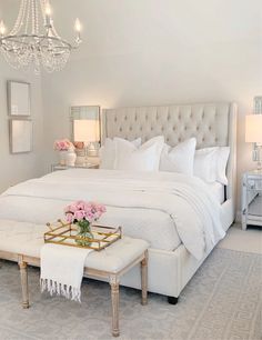 a bedroom with white furniture and chandelier