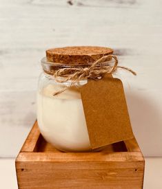 a jar filled with white liquid sitting on top of a wooden box next to a tag