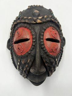 an african mask with red eyes and braids