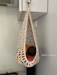 a crocheted bag hanging from a hook on the wall next to a stove