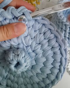 someone is crocheting the yarn on top of an object with scissors in their hands