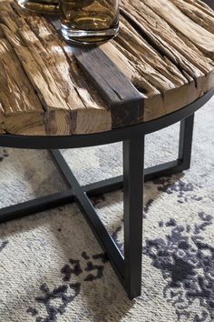 a wooden table sitting on top of a rug next to a glass vase filled with water