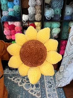 a large sunflower sitting on top of a rug in front of some yarns