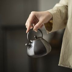 a person holding a tea kettle in their hand