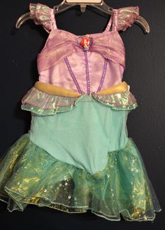 New Disney Store ARIEL Little Mermaid Costume Dress Infant Size 3-6 Months Your little mermaid will be a splash hit wherever she goes in this Ariel Costume for Baby. Foil bubbles decorate the tulle top skirt while iridescent ruffles, golden detailing and sequins will bring a sea change to this fairytale outfit. Authentic Disney Princess Costume Heart-shaped Ariel cameo Shimmering bodice features decorative embroidery and sequin trim Waist features two iridescent layers and gold lamé detail Elast Little Mermaid Dress Baby, It’s A Small World Baby Dress, Little Mermaid Baby Dress, Mesh Top Layering, Ariel Costumes, Mermaid Top, Little Mermaid Costume, Disney Princess Costumes, Tulle Top