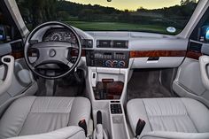 the interior of a car with white leather and wood trims, including steering wheel