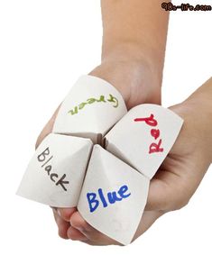 a hand holding four dices with words on them that spell out blue, red, and green