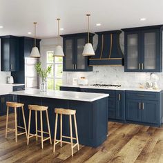 a large kitchen with blue cabinets and white counter tops, wooden flooring and stools