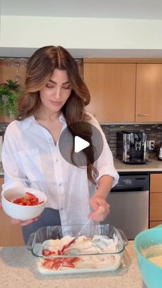 a woman standing in front of a counter preparing food on top of a glass bowl