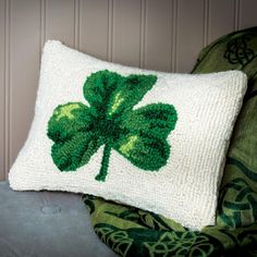 a green and white pillow with a four leaf clover design on the front, sitting on a chair