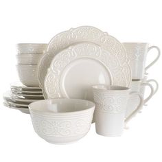 white dishes and cups are stacked on top of each other in this set, with intricate designs