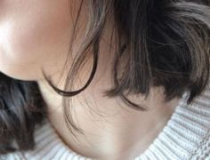 a close up view of a woman's neck with hair blowing in the wind