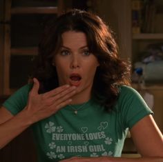 a woman in a green shirt holding her mouth open