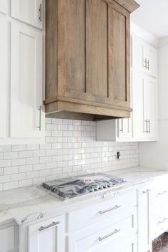 a stove top oven sitting inside of a kitchen next to white cupboards and drawers