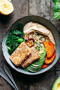 a bowl filled with meat, vegetables and other foods on top of a wooden table