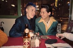 two people sitting at a table with drinks and condiments in front of them