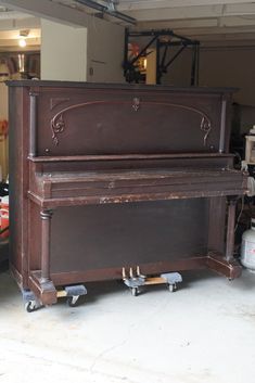 an old piano sitting on wheels in a garage