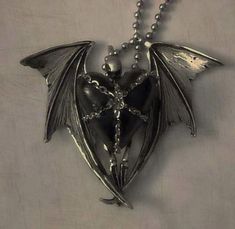 a silver necklace with a dragon on it's back and wings hanging from the front