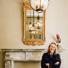 a woman standing in front of a fire place with a bird on top of it