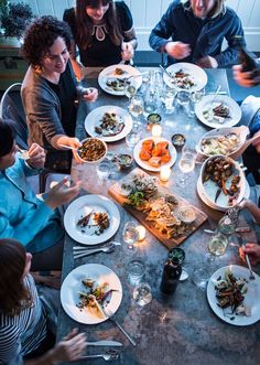 a group of people sitting around a table with plates and bowls of food on it