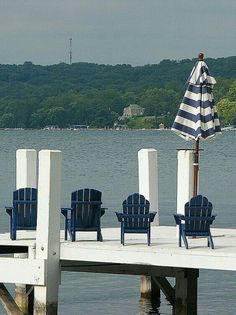 blue chairs and an umbrella on a dock