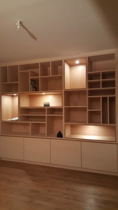 an empty living room with wood flooring and built in shelving units on the wall