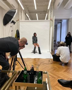 two people are taking pictures in front of a white backdrop while another person is on the floor