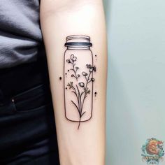 a woman's arm with a jar filled with flowers on the left side of her arm