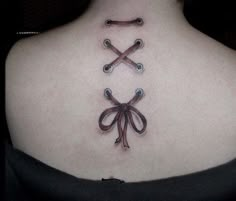 a woman's back neck with two crossed knives on it and a bow in the middle