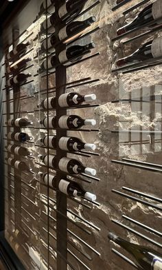 a wine rack in front of a window with bottles hanging on the glass and behind it is a marble wall