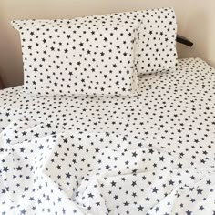 a bed with black and white stars on it's sheets, pillows and pillowcases