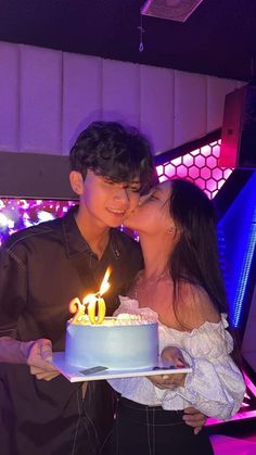 a man and woman kissing while holding a birthday cake