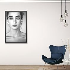 a black and white photo of a woman's face on the wall next to a blue chair